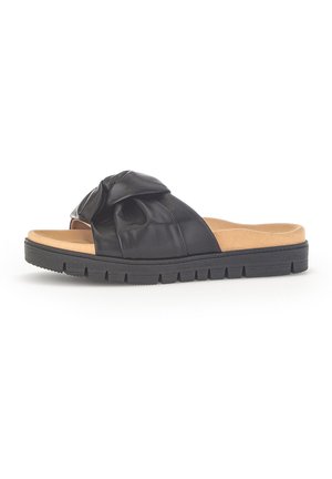 Sandalo nero in pelle tipo slide con tomaia annodata, soletta imbottita color cuoio e suola spessa nera scolpita, mostrato di profilo su sfondo bianco.