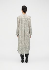 Μακρύ, ελαφρύ φόρεμα από ημιδιαφανές ύφασμα, με ανοιχτό γκρι λεοπάρ μοτίβο. Μακριά μανίκια, στρογγυλεμένος λαιμός και άνετη εφαρμογή.