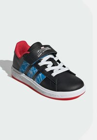 Svarta sneakers med vita snören, röd insida och blå spindelnätsdetaljer. Utrustade med ett kardborreband och strukturerad vit sula.