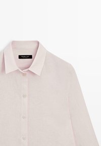 Světle růžová lněná košile s dlouhým rukávem, klasickým límečkem a zapínáním na knoflíky vpředu, zobrazuje horní polovinu a štítek uvnitř límečku.