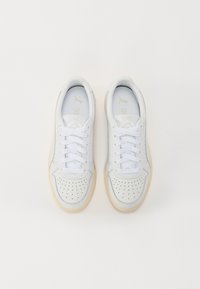 Zapatillas de piel blanca con detalles perforados, cordones blancos planos y suela de goma crema. Cuentan con un forro suave y un branding sutil en la lengüeta.