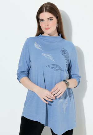 Blaues Langarmshirt mit hoher Kragen, versehen mit weißen Blätternmustern. Hergestellt aus weichem Material mit lockerer Passform und asymmetrischem Saum.
