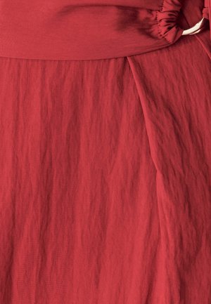 Roter, strukturiertes Gewebe mit einem gerafften Taillenbund und drapierter Optik. Glatte Oberfläche mit dezenten Falten, die die Struktur des Kleidungsstücks betonen.