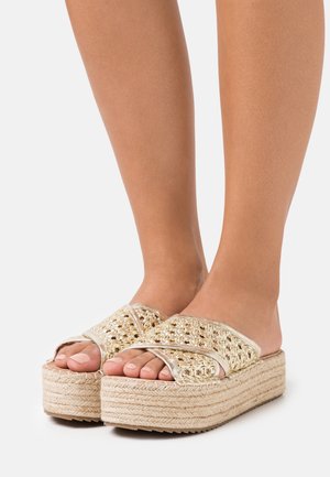 Sandales à plateforme espadrilles avec une tige métallique tissée, semelle en corde beige, bout ouvert et design à brides croisées.