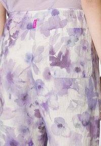 Lichte stoffen broek met een bloemenpatroon in paarse en witte tinten, met een elastische tailleband en een achterzak.