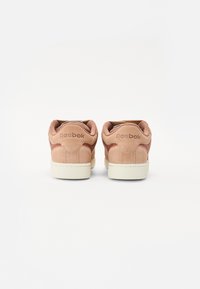 Sneaker Reebok, con tomaia in morbido suede rosa, punta rotonda e suola in gomma color crema. Branding discreto sul tallone con una finitura testurizzata.