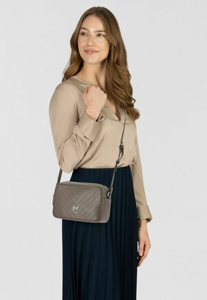 Sac bandoulière matelassé gris en cuir, présentant un motif chevron et une quincaillerie de couleur argentée. Sangle ajustable pour un port polyvalent.