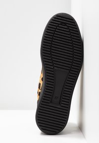 Kengät leopardikuvioisella pinnalla, joissa on pörröinen tekstuuri ja musta kumipohja, jossa on vaateridun vaakasuorat urat. Pohjassa on ilmoitettu koko 37.