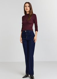 Dunkelburgunderfarbener, gerippter Langarm-Top kombiniert mit hoch geschnittenen, dunkelblauen Jeans aus Denim, die mit Kontrastnähten und einem geraden Bein-Design versehen sind.