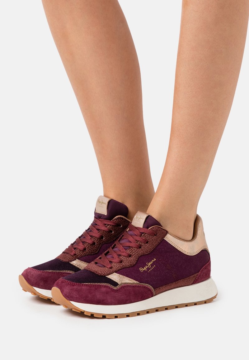 Bordeaux sneakers i mocka och mesh-material, med strukturerade detaljer, platta snören och gummisula. Guldbranding på sidan.