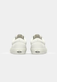 White leather Vans sneakers with a low-top design, rounded toes, and a rubber sole. Features stitched accents and logo on the heel.