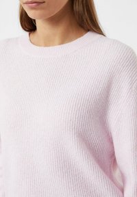Jasnoróżowy sweter w prążki z okrągłym dekoltem, miękką teksturą i lekkim stretch'em. Zaprojektowany z myślą o komfortowym dopasowaniu i luźnej sylwetce.