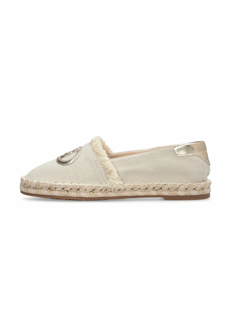 Espadrille en toile beige avec semelle en jute tressée, bordure à franges, emblème métallique sur le dessus et patch métallique au talon, vue de profil latéral.