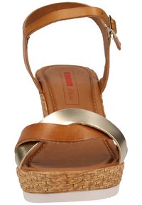 Sandale à talon compensé en cuir marron avec une semelle à texture tissée, une bride en métal doré et une boucle ajustable à la cheville.