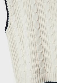 Pull sans manches en maille ivoire avec un motif torsadé texturé. Présente un ourlet côtelé et une bordure bleu marine foncé le long de l'encolure et des emmanchures.