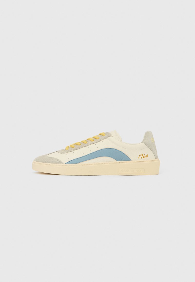 Tennisejalanõu kreemjas lõuendpealisega, hele sinine küljetriipega, halli seemisnahast ninaosaga, kollaste paeltega ja kontsakingal oranži värvi "1964" detailiga.