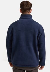 Marineblauer Fleece-Pullover mit hohem Kragen, strukturierter Oberfläche und Rückennahtdetails. Weiches Material und entspannte Passform, ideal für die Freizeit.