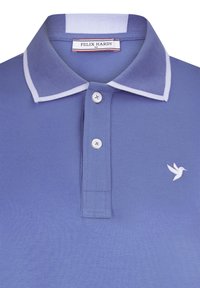 Hele helesinine polo särk, mis on valmistatud tekstureeritud riidest. Omab valget triibulist krae, kolme nuppu ja väikest valget linnulogo rinna peal.