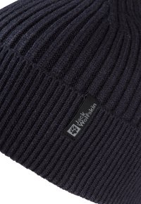 Beanie a costine di colore grigio scuro con un piccolo etichetta nera del logo Jack Wolfskin cucita vicino al bordo.