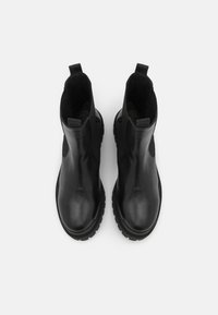 Paire de bottines Chelsea en cuir noir avec panneaux latéraux élastiques et languettes de tirage, vue de dessus sur fond blanc.