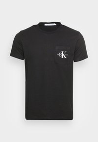Zwart katoenen t-shirt met een ronde hals, korte mouwen en een heur pocket met een wit logo en de tekst "Calvin Klein Jeans" in een contrasterend ontwerp.