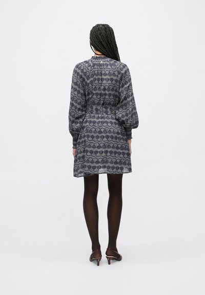 Φόρεμα με κοντά μανίκια από ύφασμα με σχέδια, σε σκουρομπλε και γκρι αποχρώσεις. Διαθέτει ζώνη στη μέση με πιέτες και μανίκια-μπαλόνι. Φορεμένο με καλσόν και ψηλοτάκουνα.