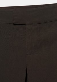 Pantalon marron à texture lisse, avec une ceinture plate, une fermeture avant dissimulée et un détail subtil de poche latérale.