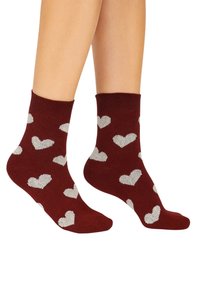 Burgunderfarbene Knöchelsocken mit einem Muster aus silbernen Herzen. Hergestellt aus einem weichen, strukturierten Material, verfügen sie über ein geripptes Bündchen für zusätzlichen Komfort.