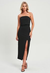 Schwarzes trägerloses Kleid mit einem taillierten Oberteil, langem Rock und einem seitlichen Schlitz, gefertigt aus glattem Material, das eine elegante Silhouette unterstreicht.