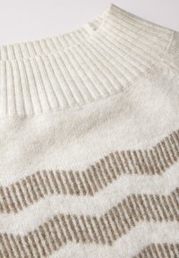 Hellbeige Strickpullover mit geripptem Halsauschnitt und strukturiertem, welligem Muster in Hellbraun. Weicher, gestrickter Stoff mit einem gemütlichen Aussehen.
