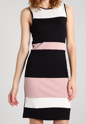 Ärmelloses knielanges Kleid mit horizontalen Farbstreifen in Schwarz, Weiß und Hellrosa, getragen von einer stehenden Frau.