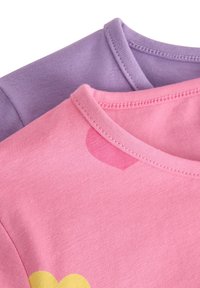 Dve tričká, jedno ružové so vzorom žltých srdiečok a jedno levanduľové, oba s rebrovaným okrúhlym výstrihom a hladkou bavlnenou látkou.