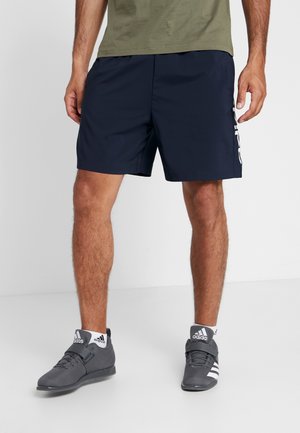 Marineblaue Shorts aus synthetischem Material mit elastischem Bund. Mit Seitentaschen und einem weißen Logo-Druck auf dem linken Bein.