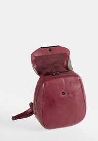 Dunkelroter Leder-Rucksack mit runder Form, Reißverschluss und weicher Textur. Verfügt über einen Magnetverschluss und ein glattes Innenfutter.