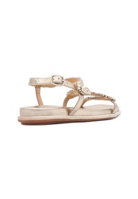 Sandali metallici oro con dettagli decorativi in gioielli, design open-toe e cinturino alla caviglia regolabile. Suola piatta con un leggero tacco.