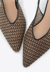 Woven czółenka na szpilce z wydłużonym noskiem w odcieniach brązu i czerni, z teksturowaną powierzchnią, z czarnym wykończeniem i przezroczystymi detalami z siateczki.