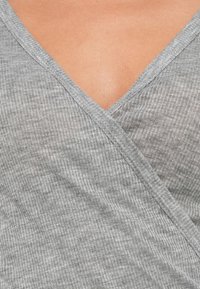 Γκρι κορυφή με ριμπ ύφανση και τύλιγμα, με βαθύ V-λαιμόκοψη και υφασμένο ύφασμα, με ορατή ραφή κατά μήκος των άκρων.