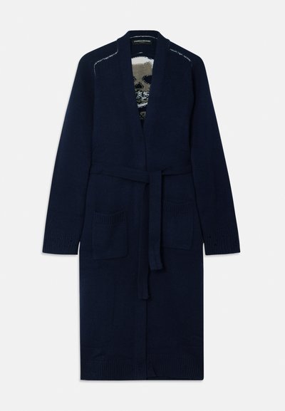 Marinblå stickad morgonrock med bälte i midjan, två framfickor och ribbade ärmslut. Har en kontrasterande mönstrad insida.