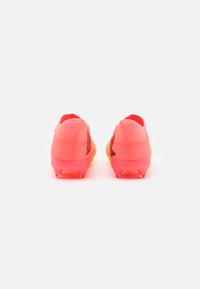 Botas de fútbol con una vibrante combinación de colores rosa y naranja. Presentan un upper de malla texturizada y una suela de goma con tacos para tracción.