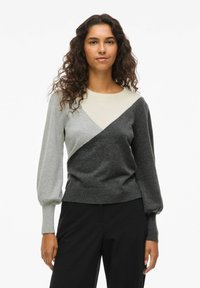 Pull à manches longues avec un design en blocs de couleurs incluant des panneaux gris, gris clair et noir, des poignets côtelés et une coupe décontractée.