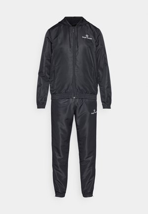 Black track suit made of smooth, lightweight nylon. Features a zip-up jacket with a hood, elastic cuffs, and matching tapered pants with side pockets.