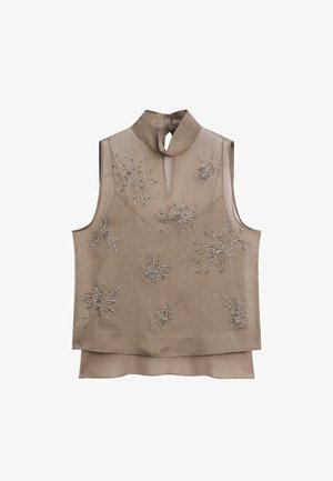Haut beige sans manches avec col montant et ouverture en forme de goutte, décoré de motifs étoilés en perles argentées sur le devant et ourlet superposé.