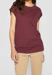 Burgundské tričko s krátkým rukávem z měkké bavlny, s kulatým výstřihem, volným střihem a prošitým lemem. Nosit s khaki cargo kalhotami.