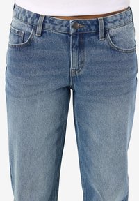 Ανοιχτό μπλε τζιν παντελόνι με ξεθωριασμένη υφή, πέντε τσέπες και κλείσιμο με κουμπί μπροστά. Ευθεία γραμμή με αντίθετες λεπτομέρειες ραφής.