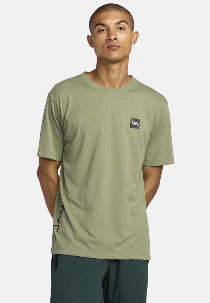 Oliwkowy t-shirt z krótkim rękawem wykonany z miękkiego materiału, z czarnym kwadratowym logo na piersi oraz czarnym detalem logo z boku.