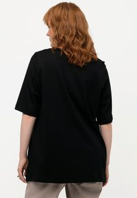 Schwarzes T-Shirt mit kurzen Ärmeln, hergestellt aus weichem Stoff. Hat einen lockeren Schnitt und einen runden Halsausschnitt, zeigt eine glatte, unverzierte Textur.