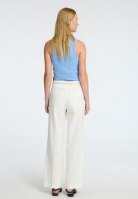 Světle modrý pruhovaný top bez rukávů se přiléhavým stylem, skombinovaný s bílými kalhotami s širokými nohavicemi. Látka vypadá jemně, má hladkou strukturu a elastický pas.