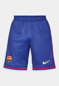 FC Barcelona sports shorts in blue polyester, featuring a gold Nike logo and club crest with red side stripes. Elastic waistband for comfort.