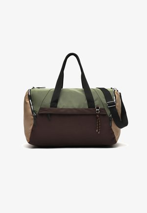Torba podróżna z zielonymi, brązowymi i beżowymi panelami, czarnymi uchwytami, przednią kieszenią na zamek oraz regulowanym czarnym paskiem na ramię.