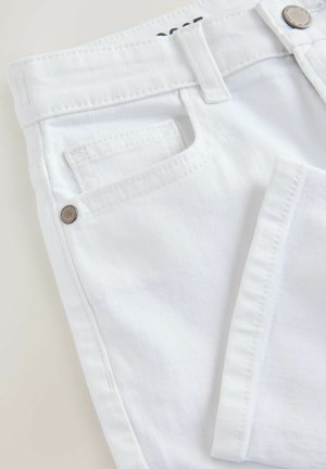 Balti džinsai iš džinsinio audinio, turintys klasikinius kirpimo, matomą priekinę kišenę, metalinį mygtuko detale ir subtilią tekstūrą. Paprastos siūlės palei kraštus.